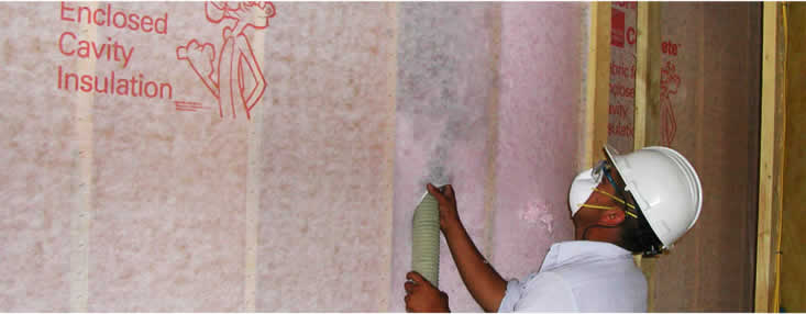 worker blowing in pink owens corning wall insulation