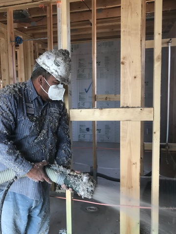 worker blowing in cellulose wall insulation