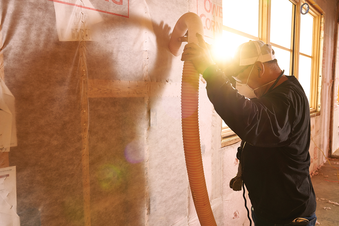 Technician blowing insulation into a wall.